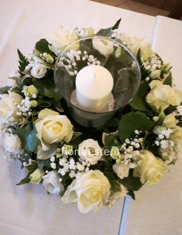 Centrotavola con vetro e candela, rose bianche, lisianthus bianco e verdi  pregiati di contorno