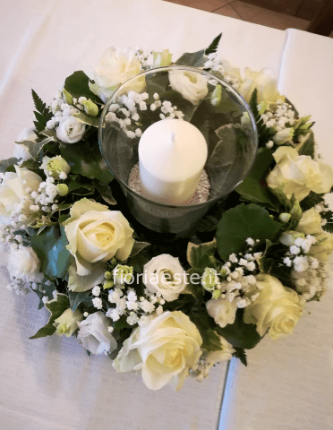Centrotavola con vetro e candela, rose bianche, lisianthus bianco e verdi pregiati di contorno